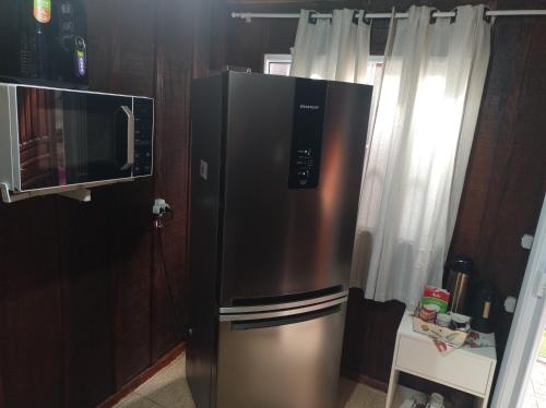 a stainless steel refrigerator in a kitchen with a microwave at Pousada 03 do vô Bi in São Francisco do Sul
