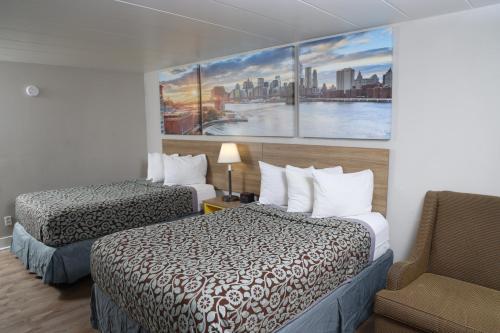 a hotel room with two beds and a chair at Days Inn by Wyndham Pittsburgh in Pittsburgh