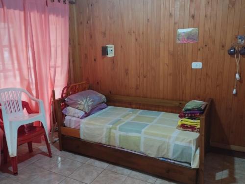 a small bedroom with a bed and a chair at Cabañas Las Moras in Candelaria