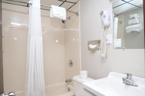 a white bathroom with a shower and a phone at Days Inn by Wyndham Pittsburgh in Pittsburgh