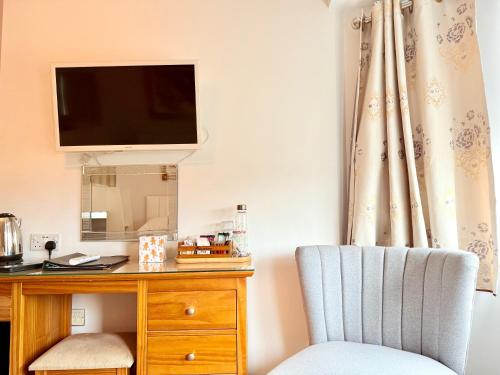 a room with a desk with a tv and a chair at Oxford Guest House in Oxford