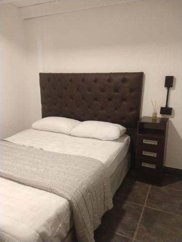 a bedroom with a large bed with a brown headboard at Hospedaje JosEva in Unquillo