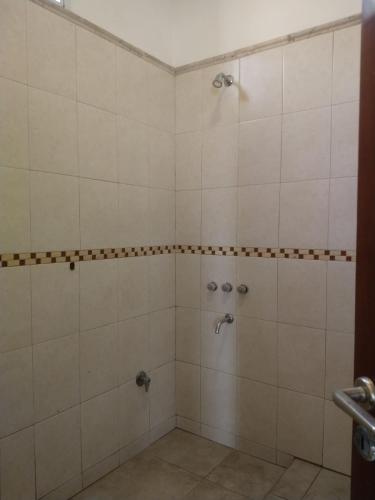 a bathroom with a shower with white tiles at Hospedaje JosEva in Unquillo