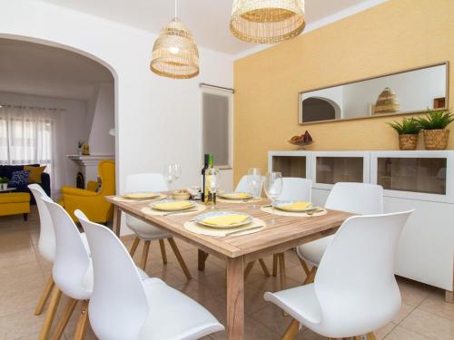 a dining room with a wooden table and white chairs at Villa Bel Mar by Stay ici in Albufeira