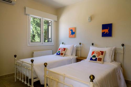 two twin beds in a room with a window at Villa Mila with private pool by Olivestone Village in Ágios Márkos
