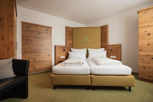 a hotel room with two beds and a chair at Haus Kristall inkl der SUPER SOMMER CARD im SOMMER 2026 in Serfaus