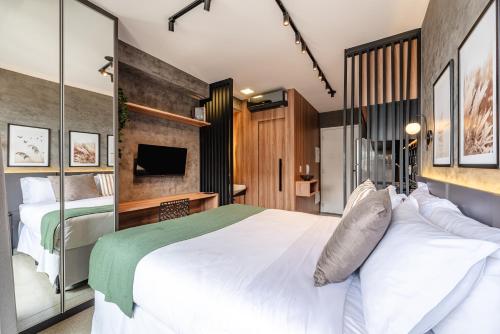 a bedroom with a large white bed and a television at Movinn Nine - Jardim Paulista in São Paulo