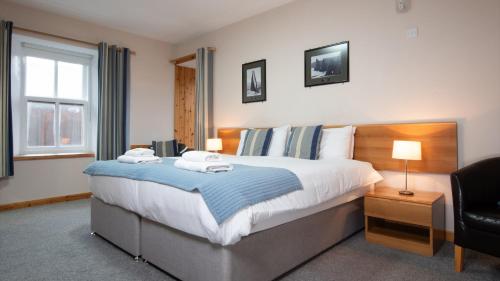 a bedroom with a large bed and a chair at Ferry Inn in Stromness