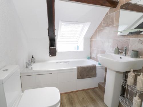 a bathroom with a white tub and a sink at Ivy Cottage in Abergele