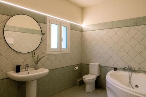 a bathroom with a sink and a toilet and a mirror at Villa Mila with private pool by Olivestone Village in Ágios Márkos