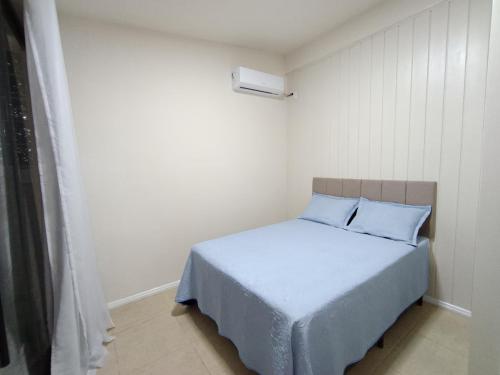 a small bedroom with a bed with blue pillows at Casa MonteFlor - Refúgio onde a vida desacelera com gentileza in Governador Celso Ramos