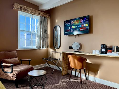 a room with a bar with a tv and chairs at The Crescent Guest House in York