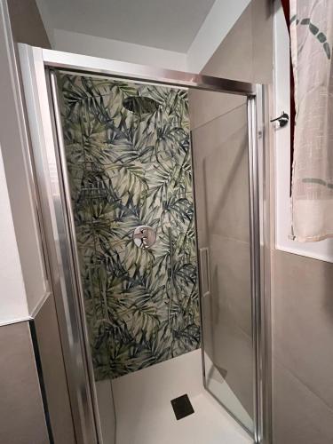 a shower with a glass door with a green plant wallpaper at Nuovo Sile in Cavallino-Treporti