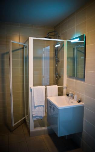 a bathroom with a sink and a shower and a mirror at Adonis La Baule in La Baule