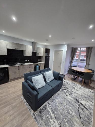 a living room with a blue couch and a kitchen at Easy access to manchester airport &city centre in Manchester