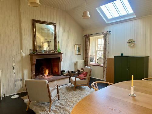 a living room with a fireplace and a table at Riverside House in Thornhill