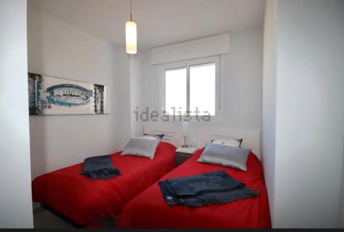 two beds in a white room with red sheets at résidence 2 chambres avec piscine proche mer in Orihuela Costa