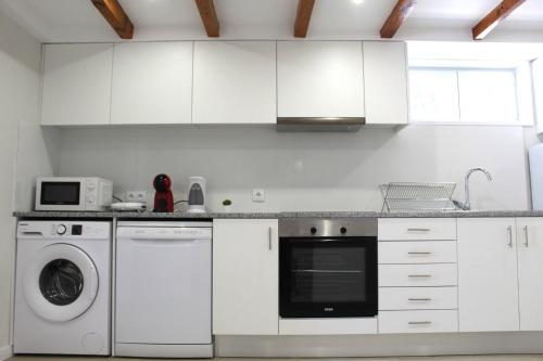 a kitchen with white cabinets and a washer and dryer at 1000Jo Apartment T2 in Gulpilhares
