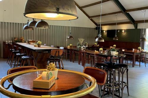 a restaurant with tables and chairs and a bar at Luxe Chalet met prachtig terras op de Veluwe , veel privacy in Hoenderloo