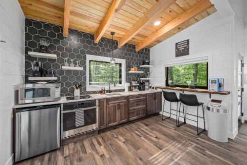 a kitchen with a sink and a counter with stools at NEW - Treehouse - Dogwood in Jonesburg
