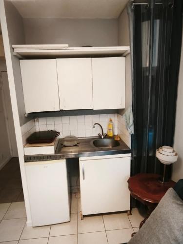 a small kitchen with white cabinets and a sink at Studio au calme in Péronnas