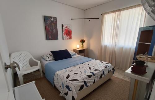 a bedroom with a bed and a chair and a window at Habitacion privada y central in Barranquilla