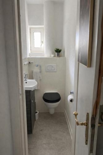a bathroom with a black toilet and a sink at Gästezimmer in Hessisch Lichtenau in Lichtenau
