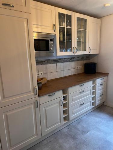 a kitchen with white cabinets and a microwave at Gästezimmer in Hessisch Lichtenau in Lichtenau