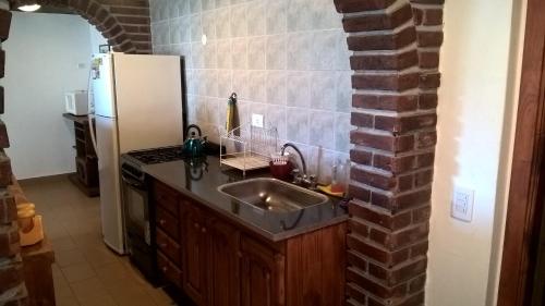 cocina con fregadero y pared de ladrillo en Playa 1, en Villa Gesell