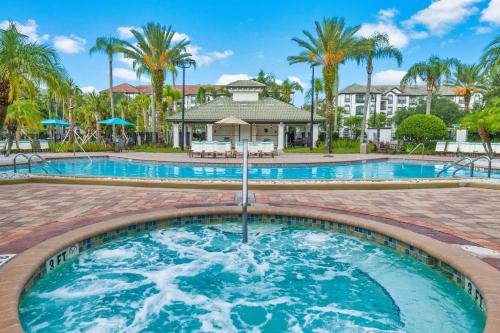 a pool with palm trees and a house in the background at Deluxe 3 Bedroom Apartment 404 in Orlando