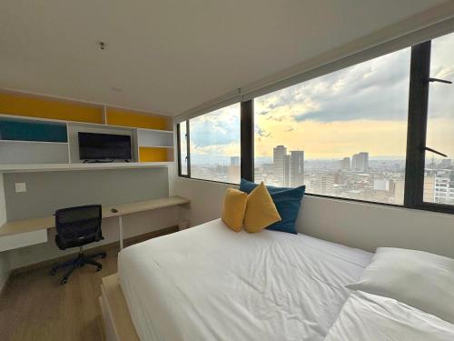 a bedroom with a bed and a desk with a window at Happa Hub Hotel in Bogotá