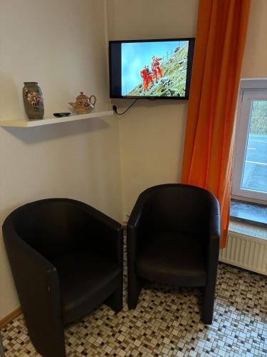 two black chairs sitting in a room with a tv at Studio Wangen in Burg-Reuland
