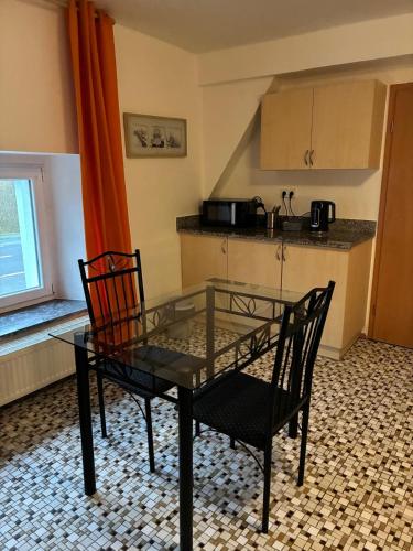 a glass table and two chairs in a kitchen at Studio Wangen in Burg-Reuland