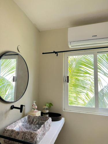 a bathroom with a mirror and a sink and a window at Casa Roca II in Isla Mujeres