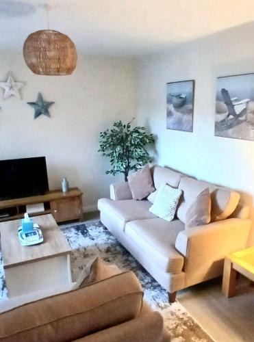 a living room with a couch and a tv at Stylish Seaside Cottage - 3 minute walk to beach with parking in Skegness