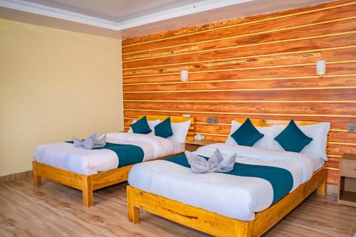 two beds in a room with wooden walls at Chautari Hotel & Restaurant in Astam