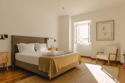a bedroom with a bed and a chair and a window at Casa do Gadanha in Estremoz