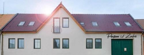 a white building with a red roof and a green door at Penzion Zacha se sklípkem in Vracov