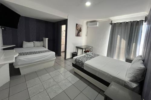 a hotel room with two beds and a television at Hotel & Suites Bausan in Boca del Río