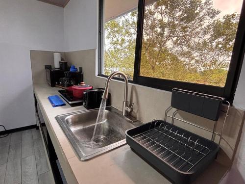 a kitchen counter with a sink and a window at Harmony Home La Fortuna in Fortuna