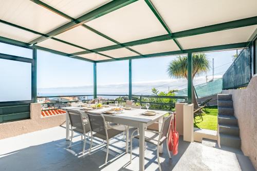 a dining room with a white table and chairs and large windows at Johns Villa by Homie in Canhas