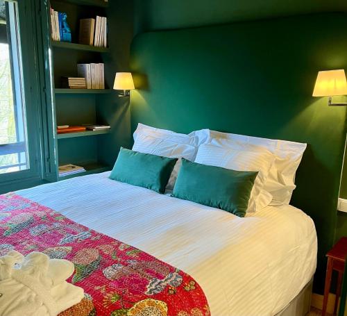 a bed with two pillows and a green wall at le Pullman in Deauville