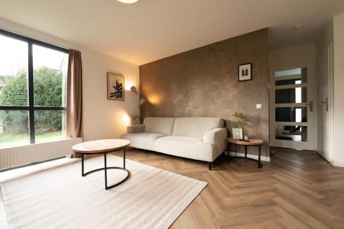 a living room with a couch and a table at Goldenescape 6P Vip huis met Royale tuin en hottub 110 in Ewijk