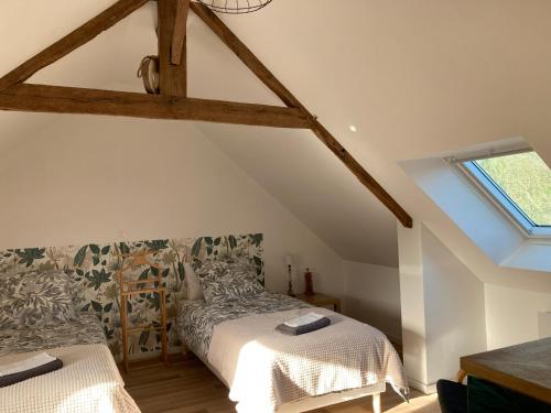 a attic bedroom with a bed and a window at La suite de L'Eau qui dort in Pleslin-Trigavou