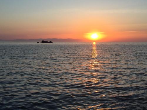a sunset over the water with a island in the distance at La casa di Grace in Seccheto
