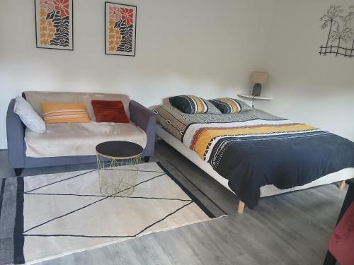 a bedroom with a bed and a couch at Studio meublé au vert - 3km de Périgueux in Boulazac
