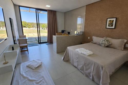 a bedroom with a large bed and a kitchen at Chalés Brisas do Lago Capitólio in Capitólio