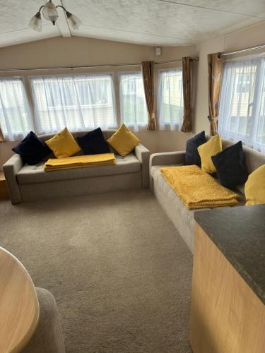 a living room with a couch with yellow pillows at Phoenix caravan hire, Trecco bay in Porthcawl