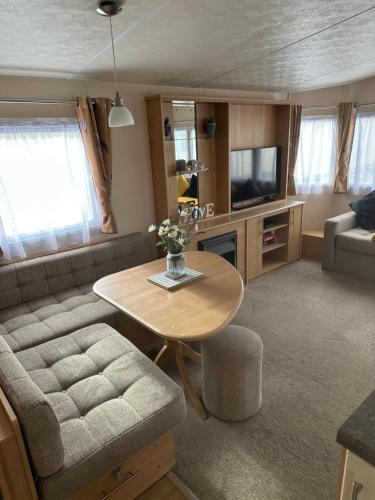 a living room with a table and a couch at Phoenix caravan hire, Trecco bay in Porthcawl