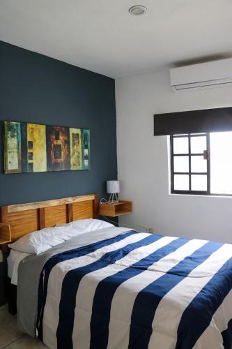 a bedroom with a bed with a blue and white striped blanket at Departamentos Perfectamente ubicados con alberca in Ciudad Madero